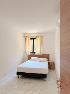 a bed in a white room with a window at Résidence Bozzi in Grosseto-Prugna +10 photos