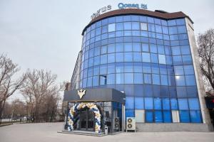 a blue glass building with a sign on it at Vogue hotel in Almaty