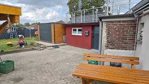 a wooden bench sitting next to a building with a red door at La Hasienda in Geldern