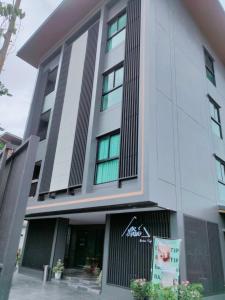 a white building with a sign in front of it at BaanTip​ HomeStay in Amphoe Phra Khanong