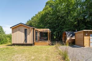 a wooden cabin in a field next to trees at The Wellness View! in Hoogersmilde