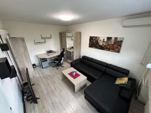 a living room with a black couch and a desk at Comfy Flat in New Belgrade in Belgrade +1 photo