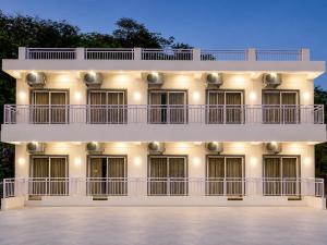 a large white building with balconies and lights at Anandi Hotel Guhagar in Guhagar