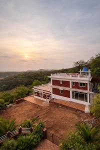 a house on a hill with the sunset in the background at Anandi Hotel Guhagar in Guhagar +13 photos
