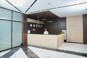 a man standing at a counter in a lobby at Vogue hotel in Almaty