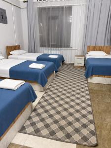 a room with four beds with blue and white sheets at Kut Hotel in Karakol