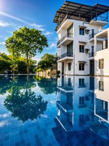 a building with a reflection in a pool of water at Shalom Resorts Yala in Tissamaharama