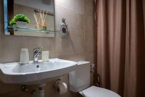 a bathroom with a sink and a toilet and a mirror at Agnanti Seaview Villa in Karlovasi +38 photos