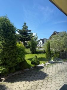 a garden with bushes and trees and a house at Góralski Apartament in Szaflary