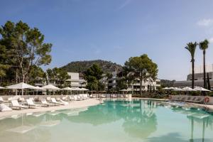 a large swimming pool with chairs and umbrellas at Kimpton Aysla Mallorca by IHG in Santa Ponsa