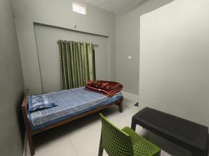 a small room with a bed and a chair at Vivek Hotel in Banbāsa