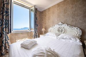 a bedroom with a large white bed with a window at Hôtel Château de la Tour Cannes in Cannes