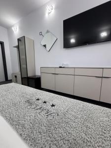 ein Wohnzimmer mit einem großen Fernseher und einem Bett in der Unterkunft Hotel Daly in Ploieşti