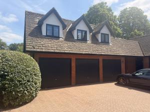 a house with four garage doors in a driveway at Wings Annexe in Beaconsfield
