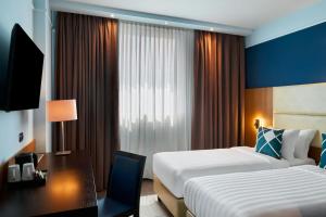 a hotel room with two beds and a desk at Four Points Flex by Sheraton Bologna Airport in Bologna +29 photos