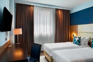 a hotel room with two beds and a desk at Four Points Flex by Sheraton Bologna Airport in Bologna