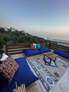 a balcony with blue pillows and a table and the ocean at Villa Ulu Piqeras in Piqeras