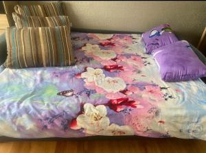 a bed with a flower blanket and pillows on it at Omes puurs in Ventspils