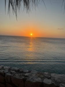 a sunset over the ocean with the sun setting at Lagun Paradise Curacao in Willemstad +29 photos
