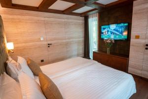 a bedroom with a bed and a flat screen tv at Хотел Дом на Алпиниста in Vratsa
