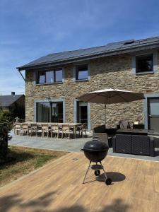 a grill with an umbrella in front of a building at La Petite Reine in Bertrix