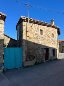 an old stone building with a blue door on a street at El Capricho de Ana in Neila de San Miguel