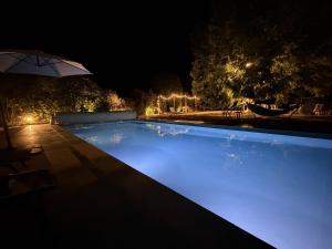 a swimming pool at night with an umbrella at La Corti in Tillières-sur-Avre