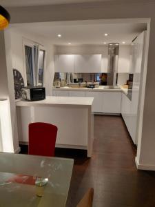 a kitchen with white cabinets and a red chair at Berner Hostel in Bern