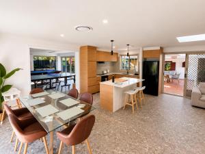 a kitchen and dining room with a glass table and chairs at Peaceful tropical retreat with pool, mineral spa & Games room in Gold Coast