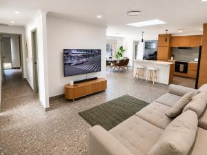 a living room with a couch and a flat screen tv at Peaceful tropical retreat with pool, mineral spa & Games room in Gold Coast