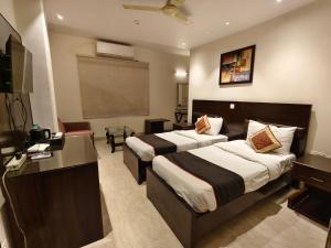 a hotel room with two beds and a desk at The Hermitage by The Cosy Hotels Near Lotus Temple in New Delhi