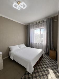 a bedroom with a large white bed and a window at Kut Hotel in Karakol