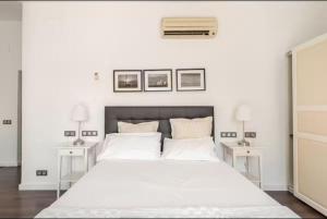 a white bedroom with a large bed with two tables at Apartament La Placeta Figueres in Figueres