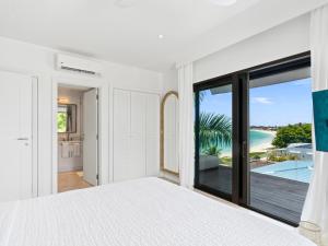 a white bedroom with a view of the ocean at La Sirène in Simpson Bay