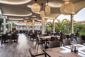 a restaurant with tables and chairs and chandeliers at Blue Lagoon Resort in Lampi