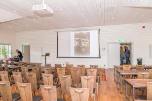 a lecture room with tables and chairs and a screen at Ulkeröds Gård in Hedekas