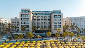 a hotel with yellow umbrellas in front of a building at Royal G Hotel & SPA 4 Star in Durrës