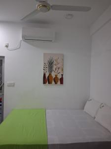 a white bedroom with a bed with a green blanket at Beach Life Long Beach Resort in Trincomalee