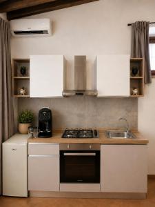 a kitchen with white cabinets and a stove and a sink at Le Bonbon in Trevignano Romano
