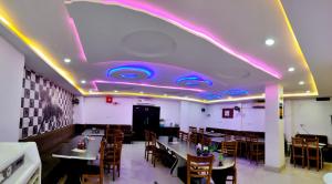 a dining room with purple lights on the ceiling at Hotel A3cube in Panna