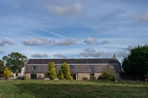a large brick building in a field with trees at Woodside Barn in Newmacher