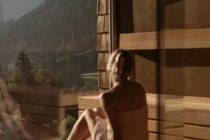 a woman sitting on a ledge looking out of a window at Hotel Marten -Joker Card Partner- in Saalbach-Hinterglemm