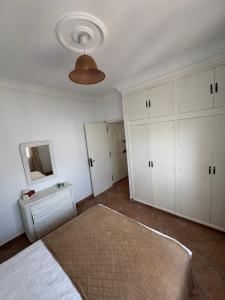 a white bedroom with a bed and a mirror at Appartement à Miramar in Martil