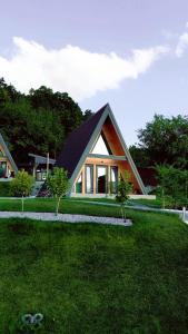 a small house with a gambrel roof on a lawn at Andrei's Refugium in Ocnele Mari
