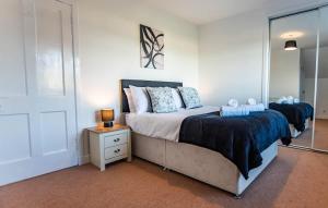 a bedroom with a large bed and a night stand at Beach House in Thurso