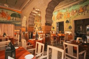 a restaurant with tables and chairs and paintings on the wall at Hotel Bissau Palace in Jaipur