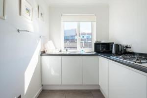 a white kitchen with a sink and a window at The Douglas - Spacious 2 bed apartment in Uddingston in Uddingston