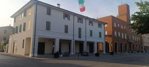 a large white building with a flag on a street at Suite IN PIAZZA in Poggio Renatico