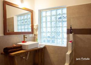 ein Badezimmer mit Waschbecken, Spiegel und Fenster in der Unterkunft Moonshine Uroa Boutique Hotel in Uroa