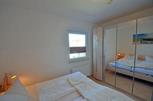 a white bedroom with a bed and a mirror at Bella Casa 34 - Strandblick in Juliusruh